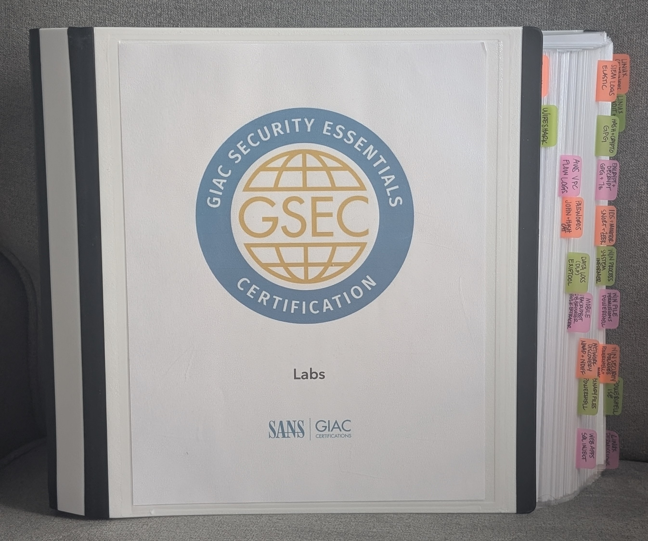 GSEC labs binder with handwritten tool names on colored tabs along the right edge, covering tools like Wireshark, John the Ripper, Snort, and others